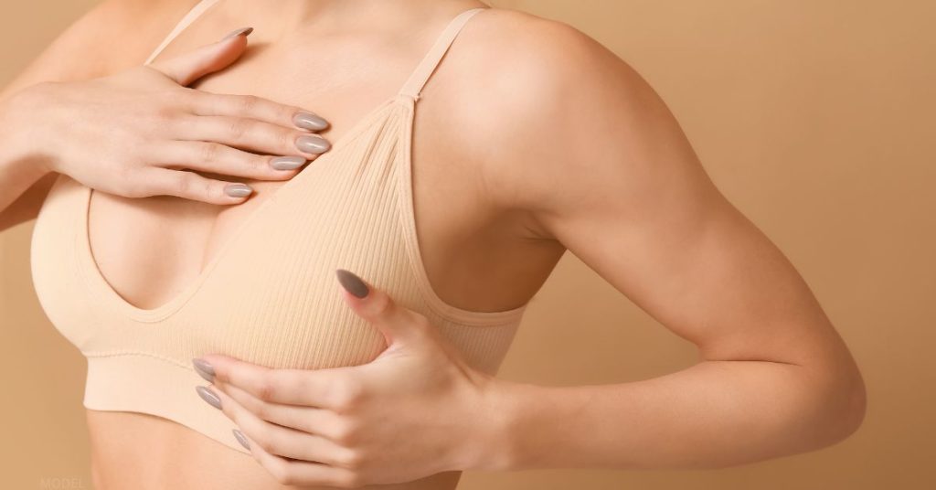 Woman in bra feeling her breast tissue (model)