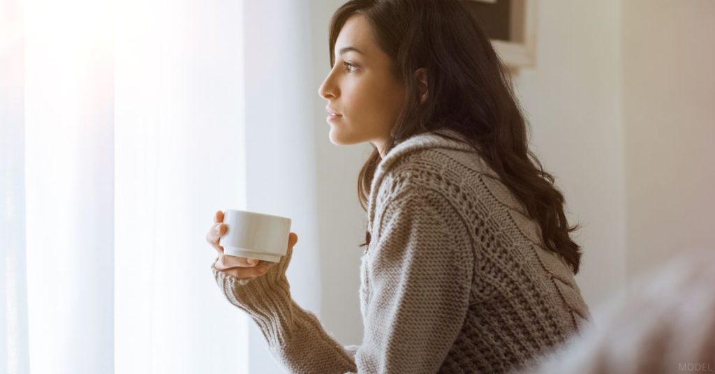 Woman holding a mug and looking off in the distance (model)